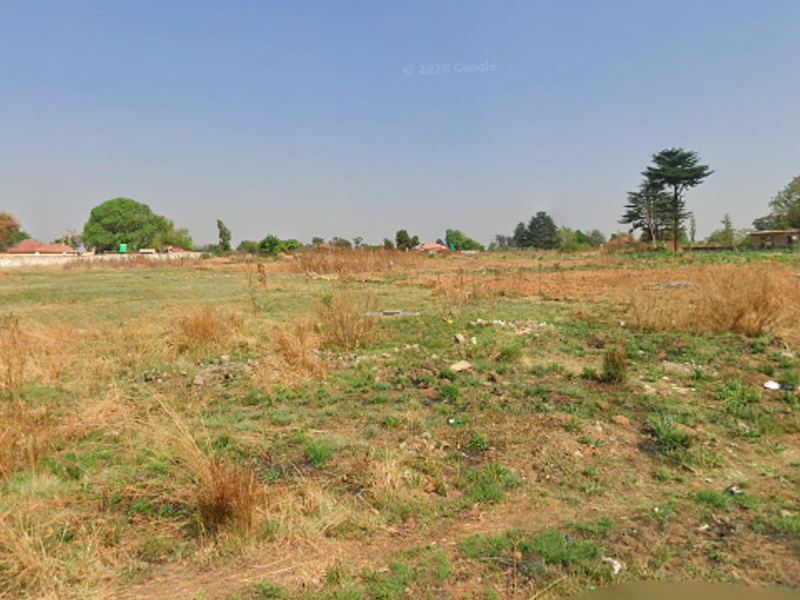 A wide-angle view of a vacant residential plot featuring open grassland and natural terrain, suitable for future development.