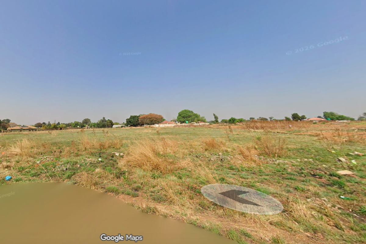 A wide-angle view of a vacant residential plot featuring open grassland and natural terrain.