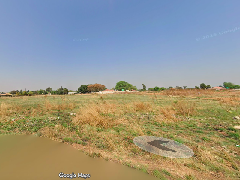 A wide-angle view of a vacant residential plot featuring open grassland and natural terrain.