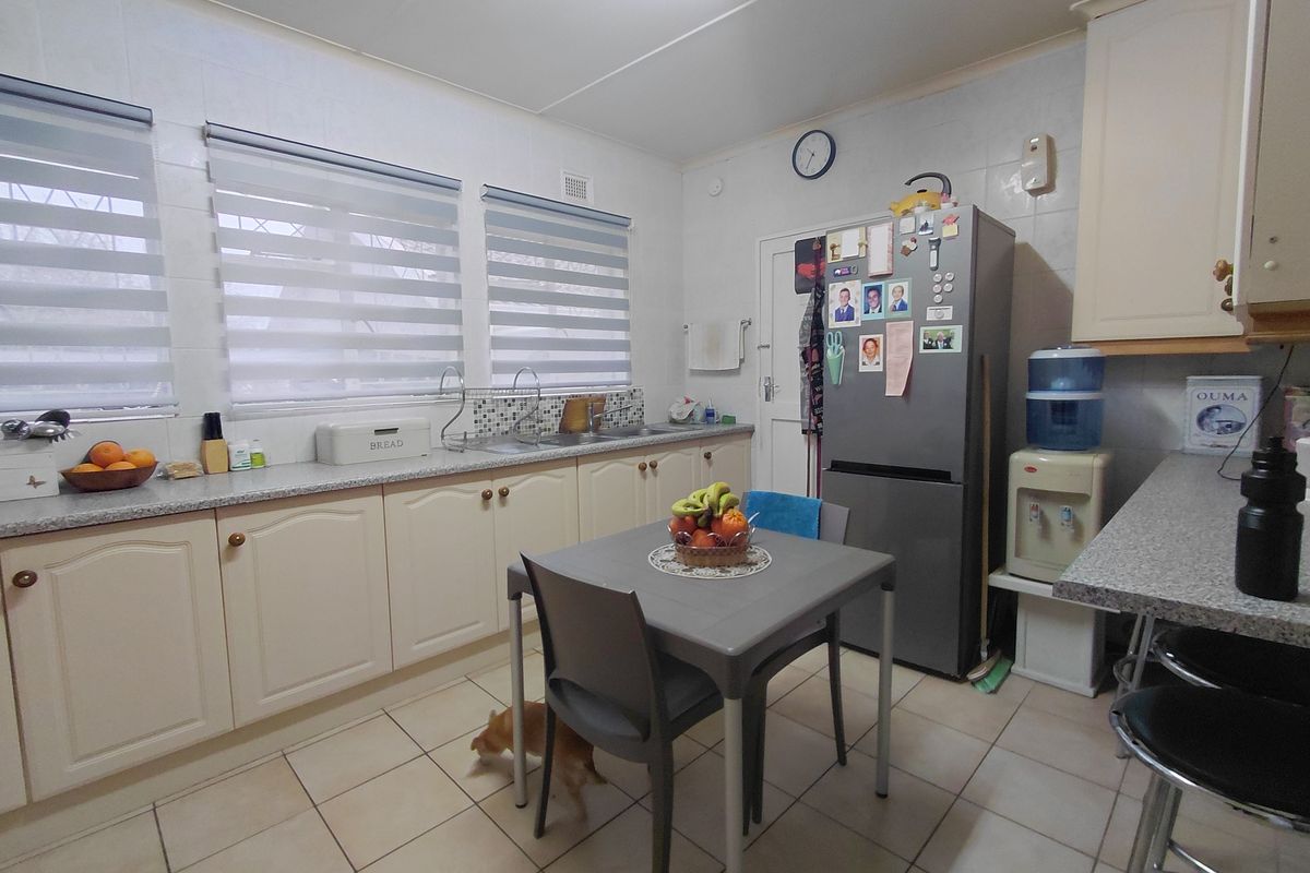 A functional kitchen featuring tiled flooring, laminate countertops, built-in cabinetry, and a double sink with a tiled splashback.
