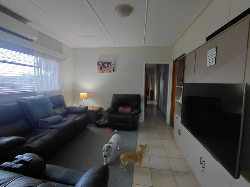 A comfortable living room featuring built-in cabinetry, split-system air conditioning, and a combination of tiled and carpeted flooring.