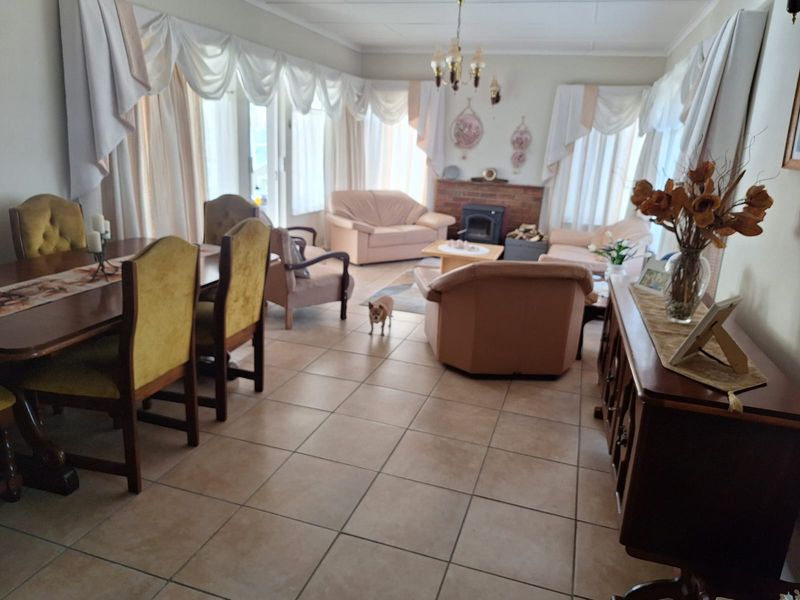 Spacious open-plan living and dining area featuring tiled flooring and a classic brick fireplace with a built-in wood burning stove.