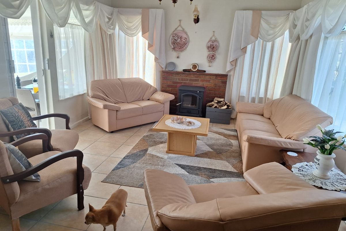 A cozy living room featuring a brick fireplace with a wood-burning stove and neutral ceramic floor tiles.