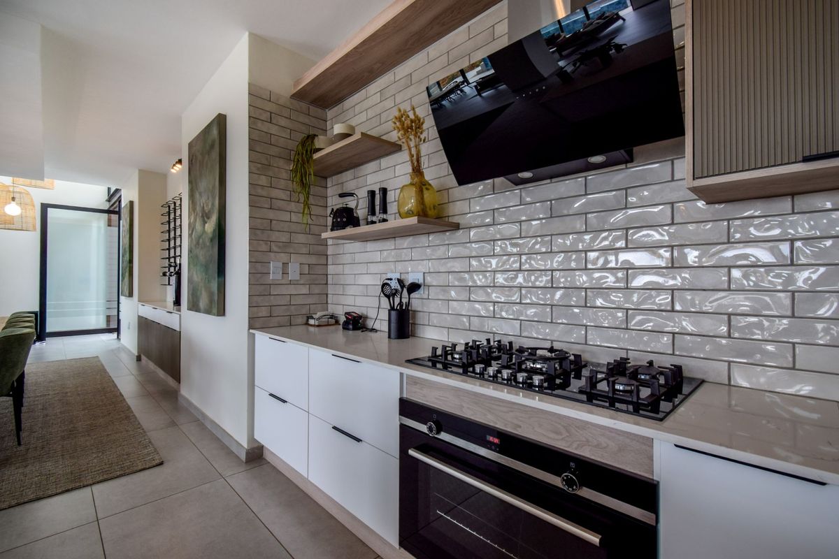 Modern kitchen featuring sleek white cabinetry, subway tile backsplash, built-in gas hob, and integrated oven with contemporary timber shelving.
