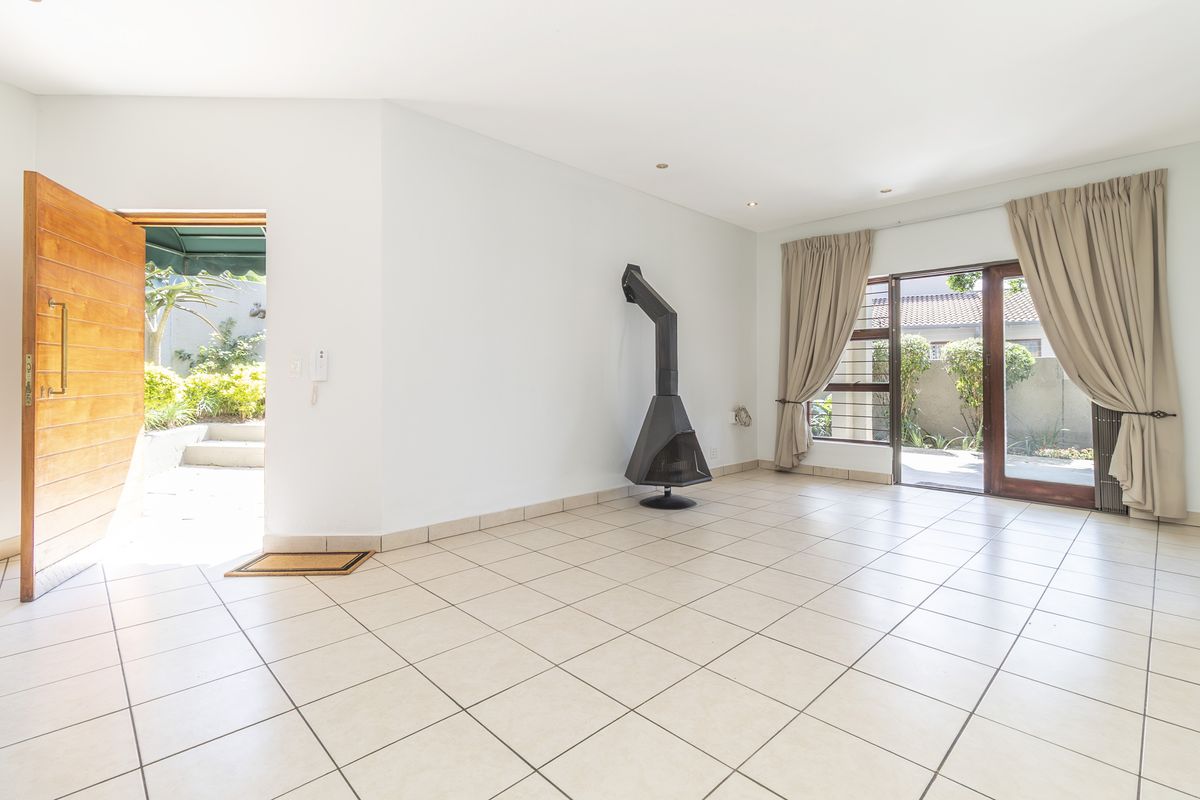 Spacious living area featuring tiled flooring, a modern freestanding fireplace, and direct access to the outdoor patio through sliding glass doors.