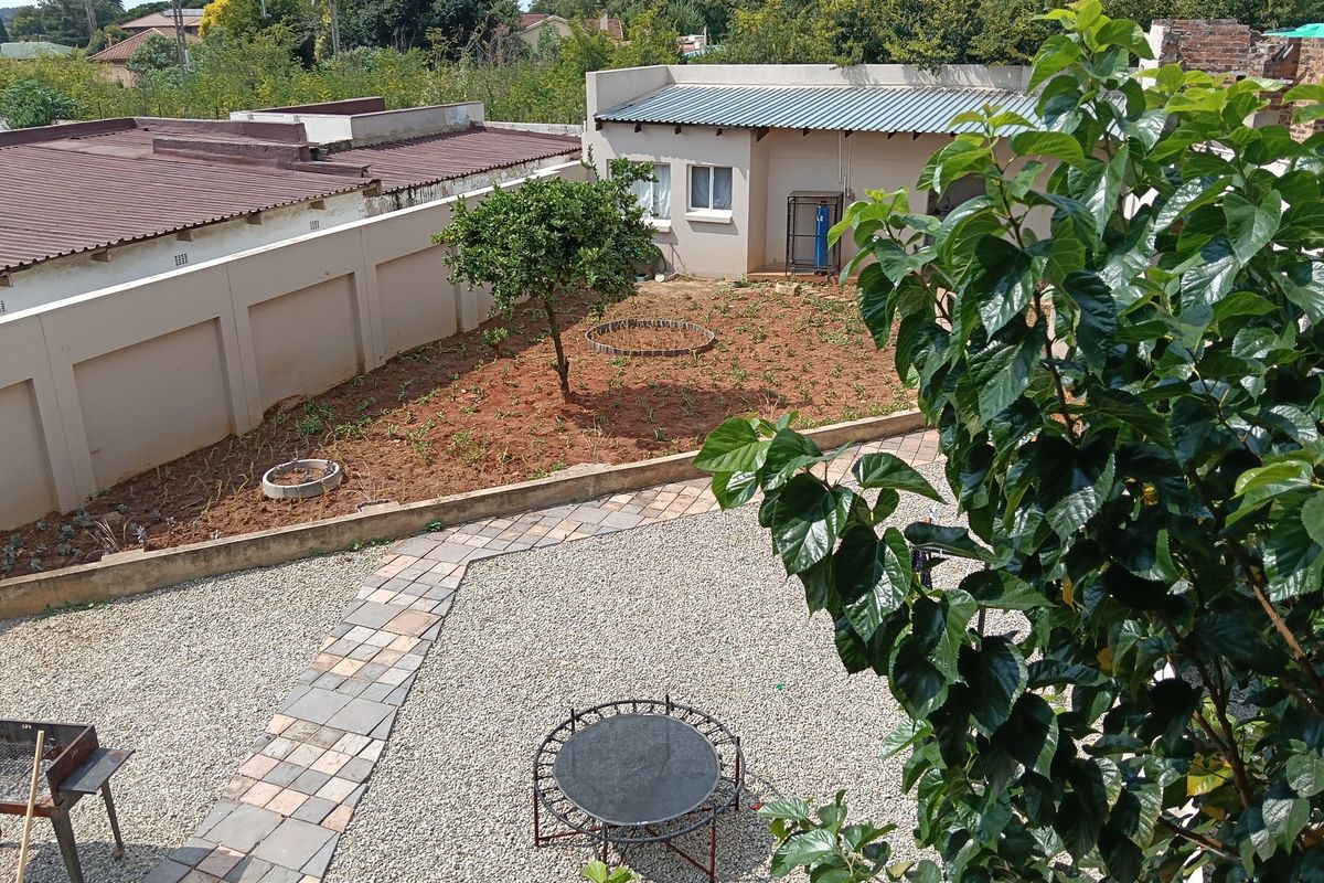 An elevated view of a rear garden featuring a gravel courtyard, paved walkway, and a section of prepared soil ready for landscaping.