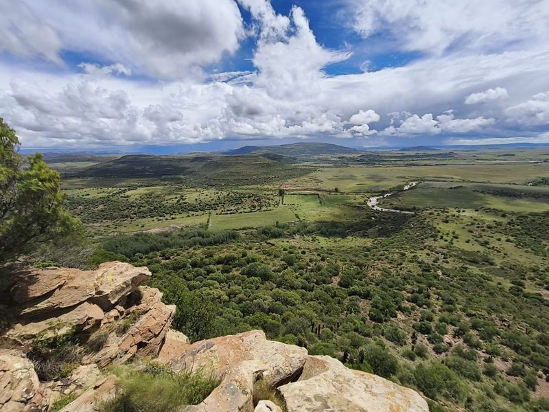 Expansive elevated landscape view overlooking the farm property, featuring rolling hills, natural vegetation, and a winding river.