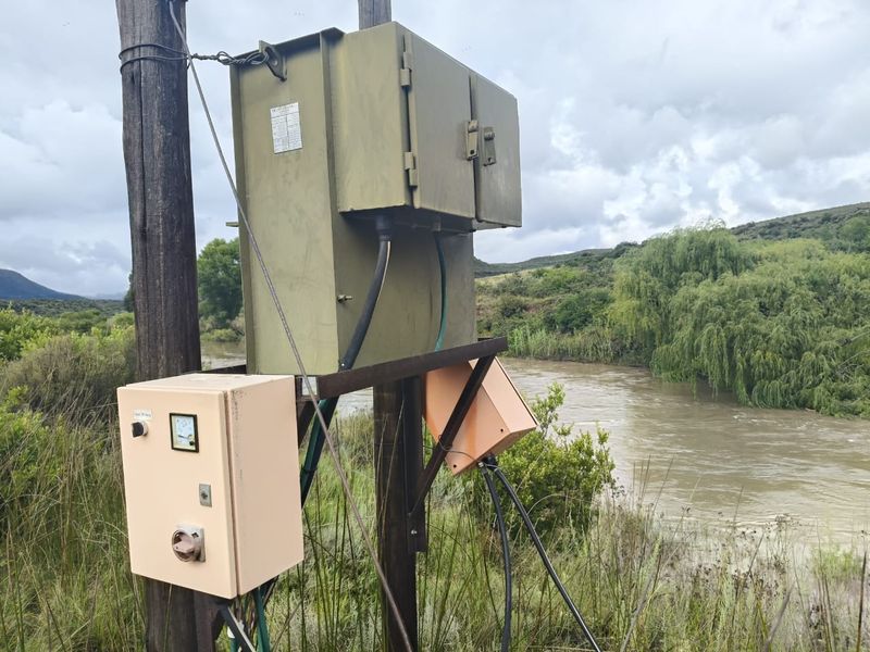 Outdoor electrical utility infrastructure and control panels situated near the riverbank on the farm property.
