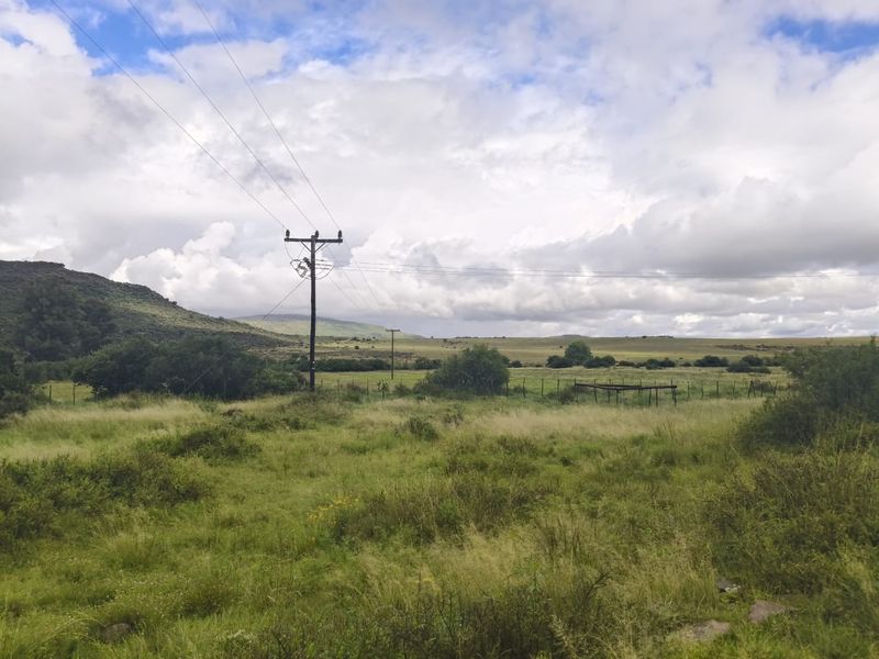 Expansive rural landscape view featuring open grasslands, rolling hills, and existing utility infrastructure on the property.