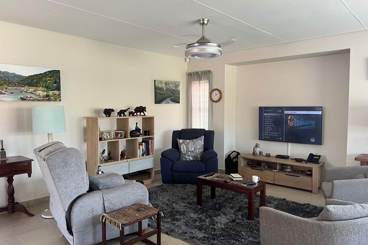 A comfortable living room featuring tiled flooring, a ceiling fan, and a recessed wall niche for media placement.