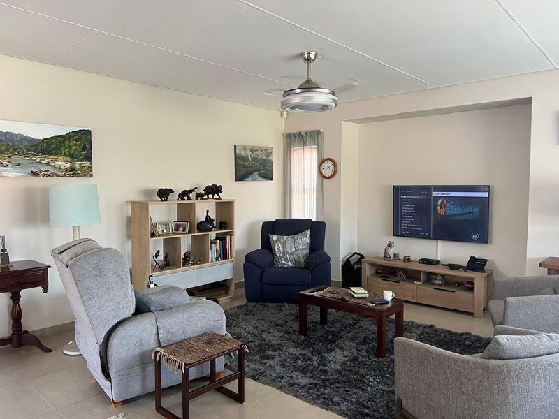 A comfortable living room featuring tiled flooring, a ceiling fan, and a recessed wall niche for media placement.