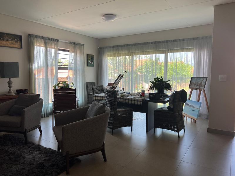 Spacious living area featuring large windows that provide ample natural light and neutral tiled flooring throughout.