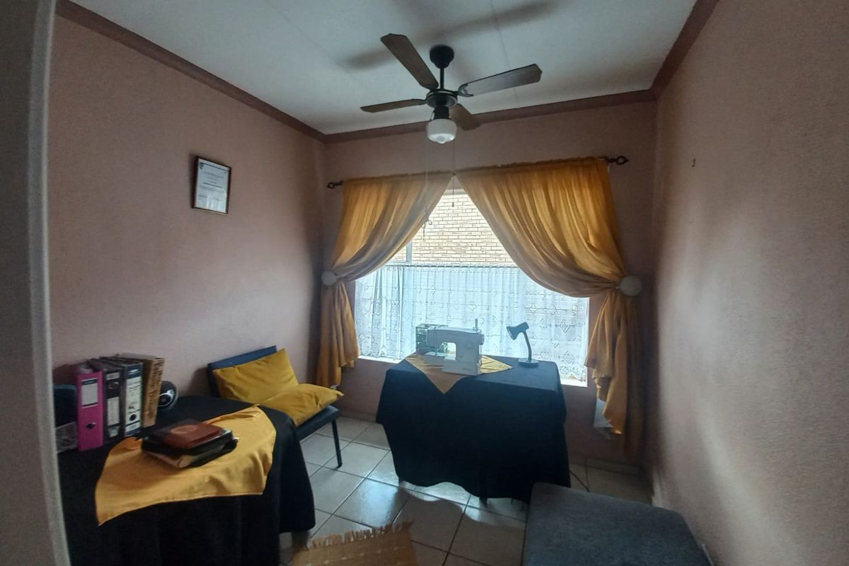 A functional bedroom space featuring tiled flooring, a ceiling fan, and neutral wall finishes, suitable for use as a bedroom or home office.