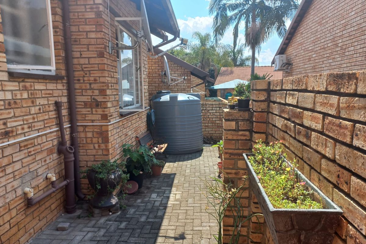 A side exterior area featuring face brick walls, a paved walkway, and a large water storage tank.