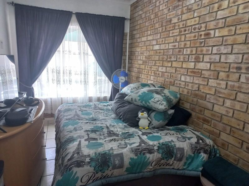 A bedroom featuring a prominent exposed brick feature wall and tiled flooring, offering a rustic aesthetic.