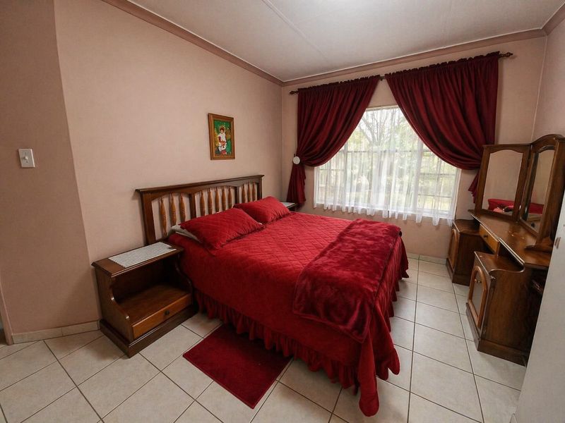 A bedroom featuring tiled flooring and a window with curtain rails, providing a functional space with neutral wall tones.
