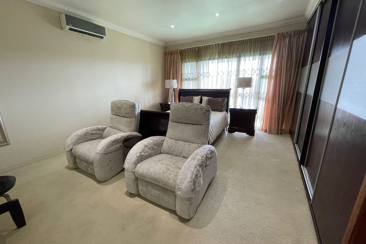 Spacious bedroom featuring a large built-in wardrobe, split-system air conditioning, and recessed lighting, offering a comfortable and functional living space.