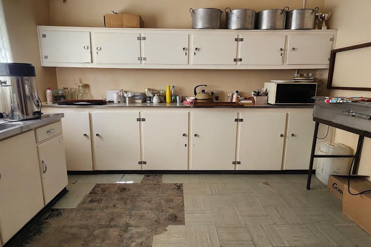 A functional kitchen area featuring built-in cabinetry, a stainless steel sink, and tiled flooring, requiring cosmetic updates to modernize the space.