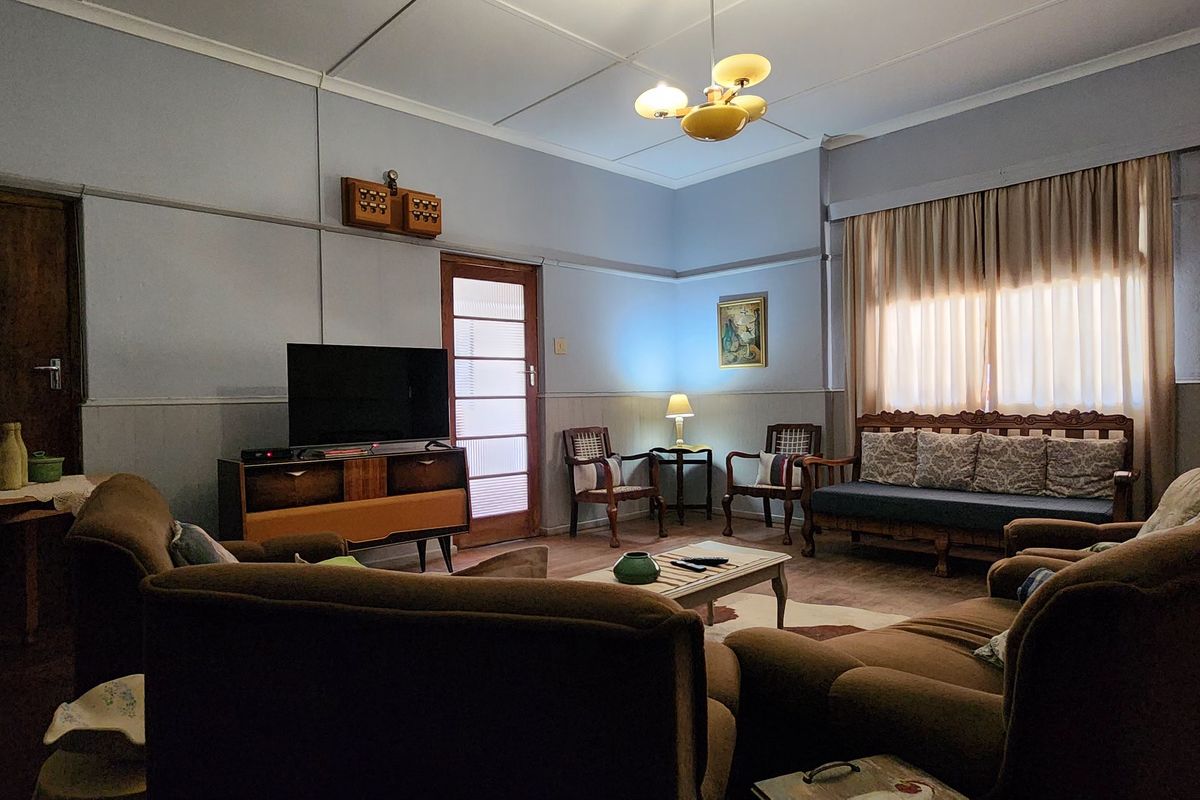 A traditional living room featuring classic architectural details, including a dado rail, high ceilings, and a glass-paneled door leading to an adjacent space.