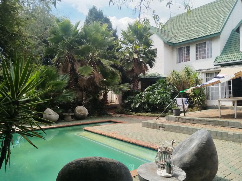 A backyard pool area featuring a swimming pool, brick paved patio, and raised terrace steps adjacent to the main house structure.