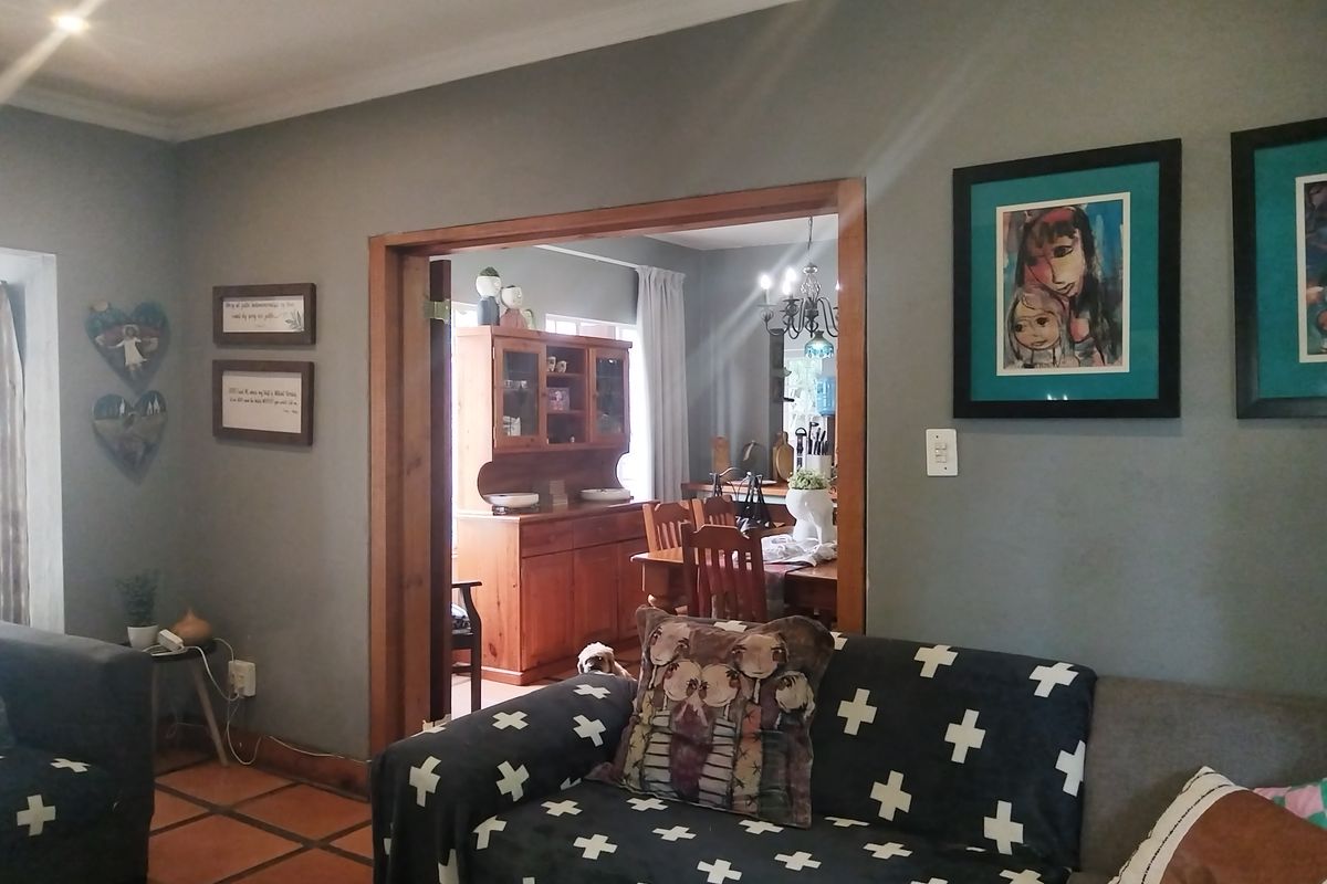 A living room featuring terracotta floor tiles and a wooden doorway leading into an adjacent dining area with a classic interior layout.