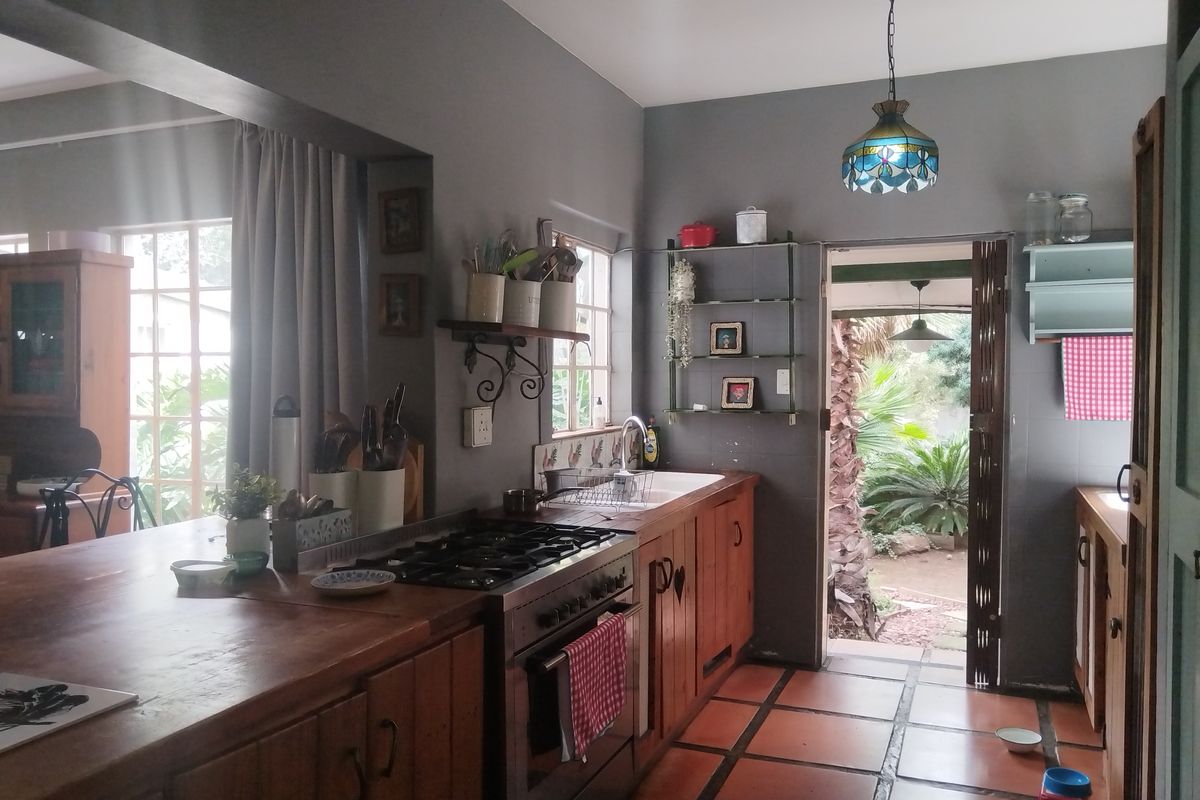 A rustic kitchen featuring wooden cabinetry, a gas stove, a ceramic sink, and terracotta floor tiles, with direct access to the garden.