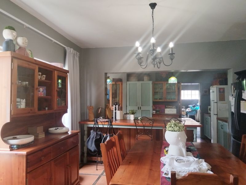 Open plan dining and kitchen area featuring a central island, built-in cabinetry, and a classic chandelier, creating a functional and connected living space.