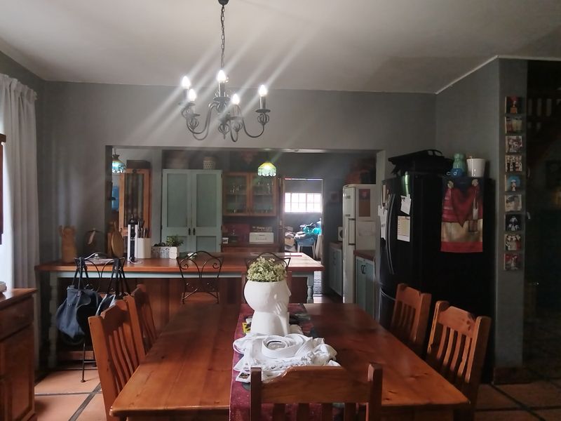Open-plan dining and kitchen area featuring a wooden breakfast bar, terracotta flooring, and a classic wrought iron chandelier.