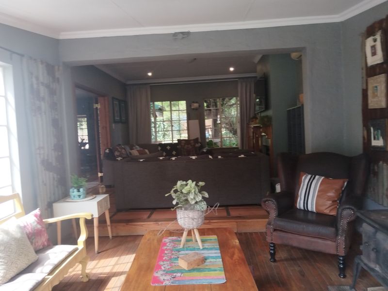 Open plan living area featuring timber flooring, a raised platform section, and a wood-burning stove, creating a cozy and connected multi-functional space.