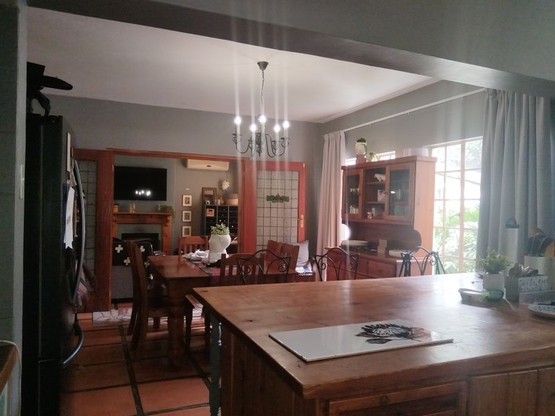 Open plan living and dining area featuring terracotta flooring, a central kitchen island, and a fireplace, creating a warm and connected family space.