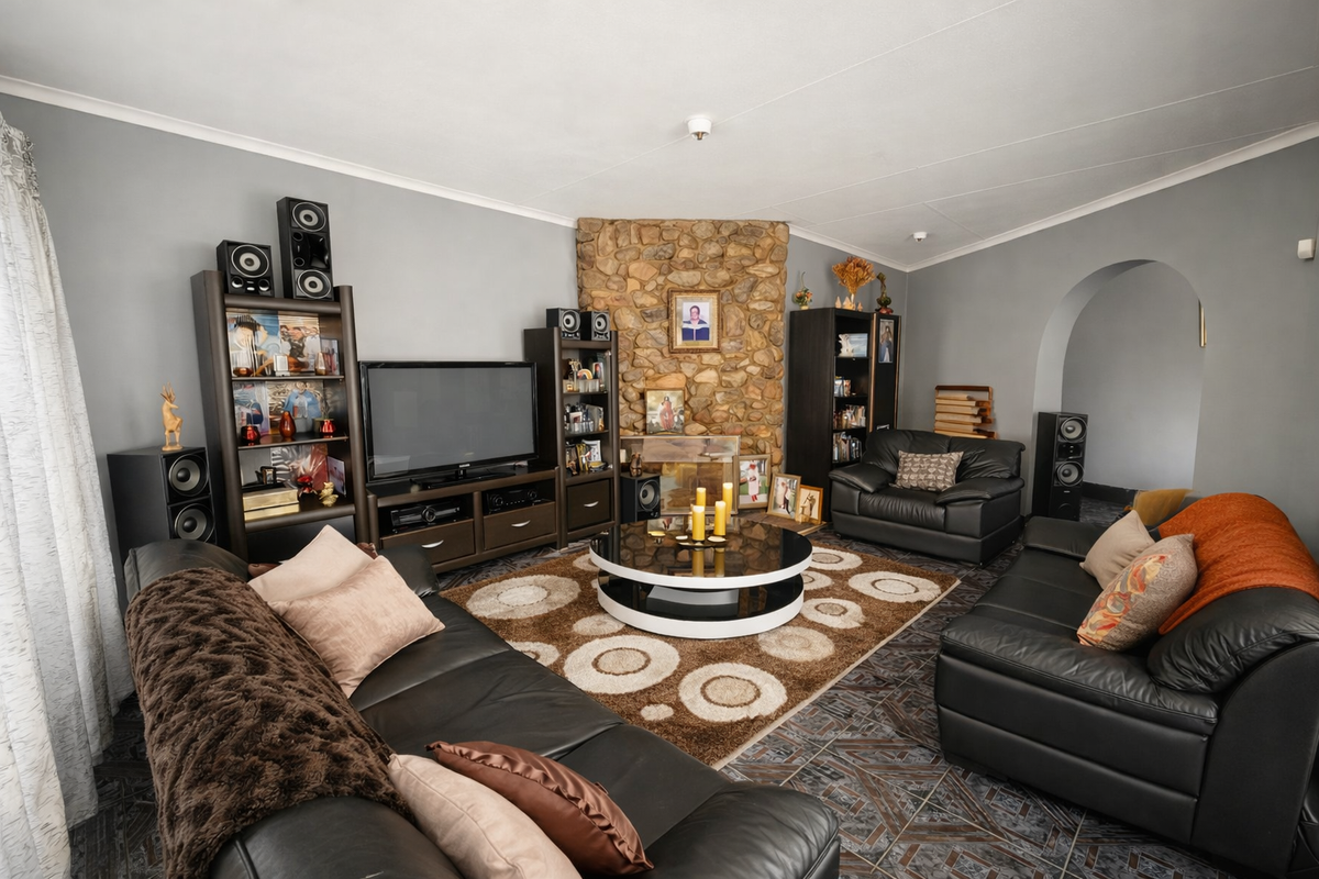 A comfortable living room featuring a prominent stone fireplace, tiled flooring, and an arched entryway leading to adjacent spaces.