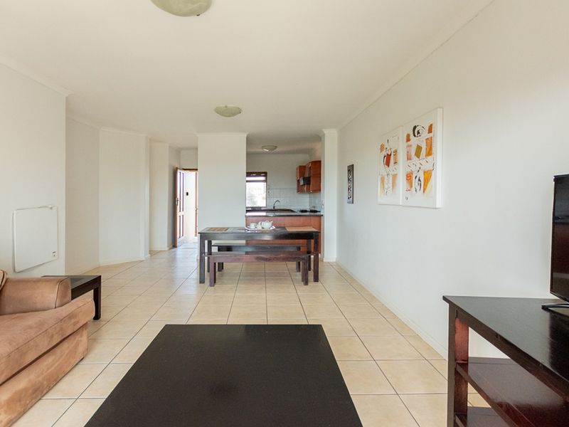 Open plan living and dining area featuring tiled flooring, leading into a functional kitchen space with built-in cabinetry.