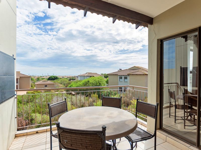 Covered balcony featuring tiled flooring, metal balustrade, and sliding glass door access, offering elevated views of the surrounding residential area.