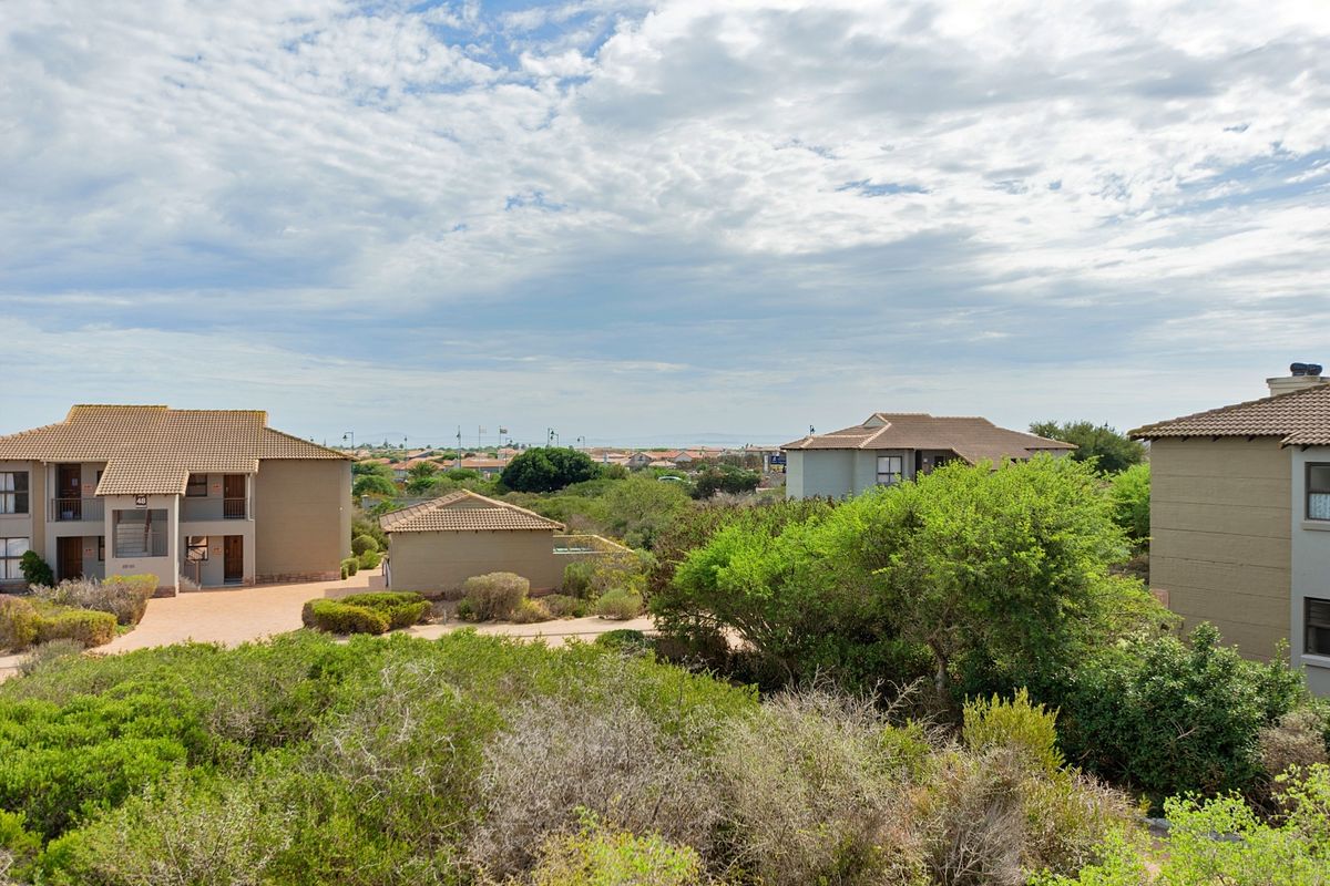An elevated aerial view of the apartment complex grounds, featuring multiple residential buildings, paved access paths, and established garden landscaping.