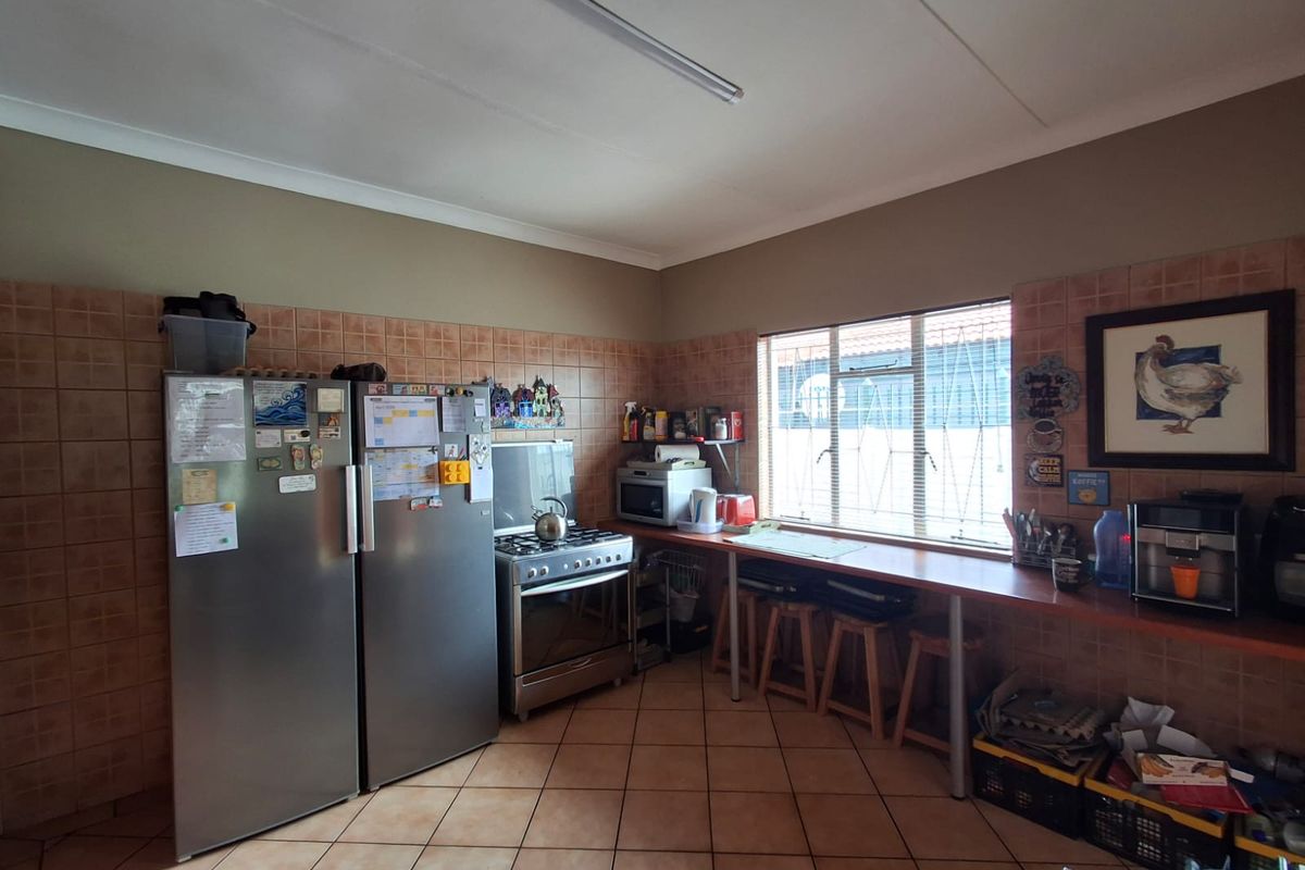 A functional kitchen featuring tiled splashbacks, tiled flooring, a freestanding stove, and a built-in breakfast bar area.