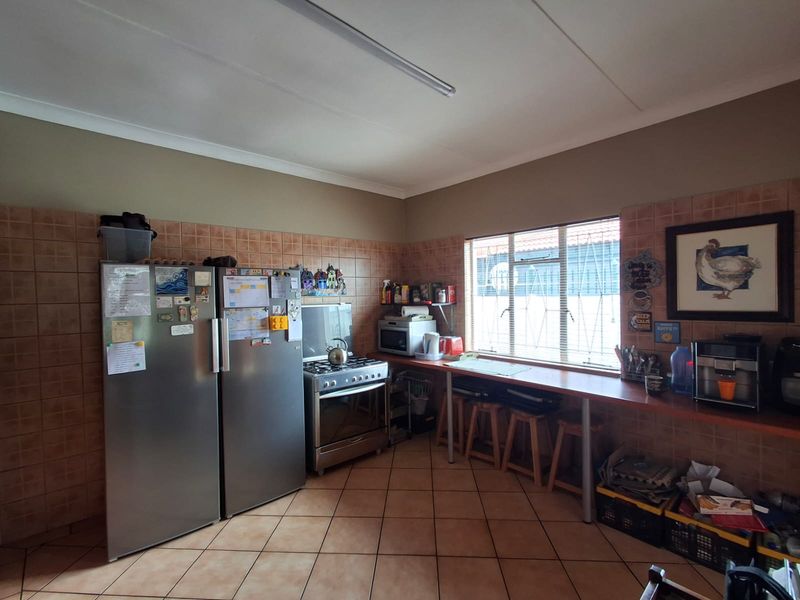A functional kitchen featuring tiled splashbacks, tiled flooring, a freestanding stove, and a built-in breakfast bar area.