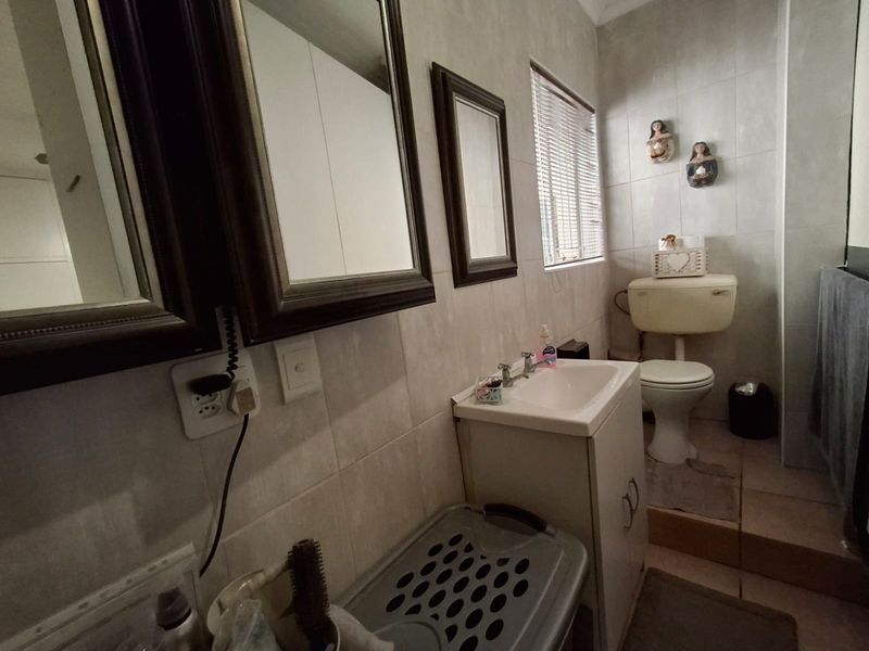 A functional bathroom featuring tiled walls and flooring, a vanity cabinet with a basin, and a standard toilet.