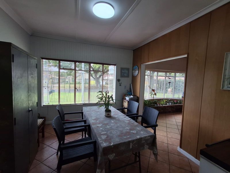 Dining area featuring tiled flooring, wood paneling, and large windows providing natural light and views into the adjacent sunroom.