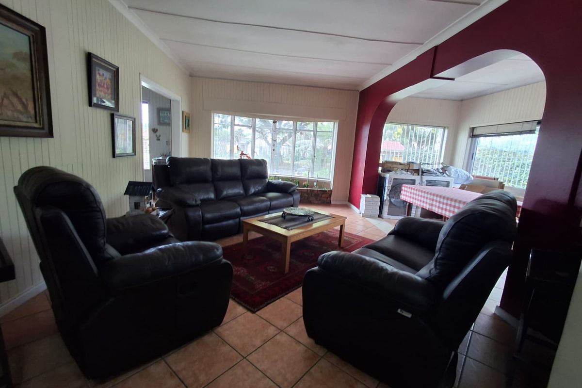 Spacious living area featuring tiled flooring, timber wall paneling, and a distinctive architectural archway connecting to an adjacent space.