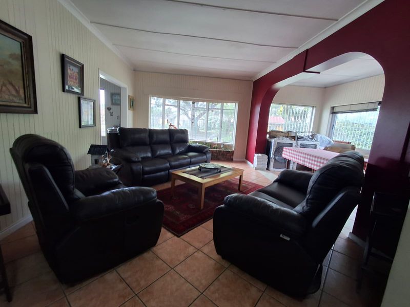 Spacious living area featuring tiled flooring, timber wall paneling, and a distinctive architectural archway connecting to an adjacent space.