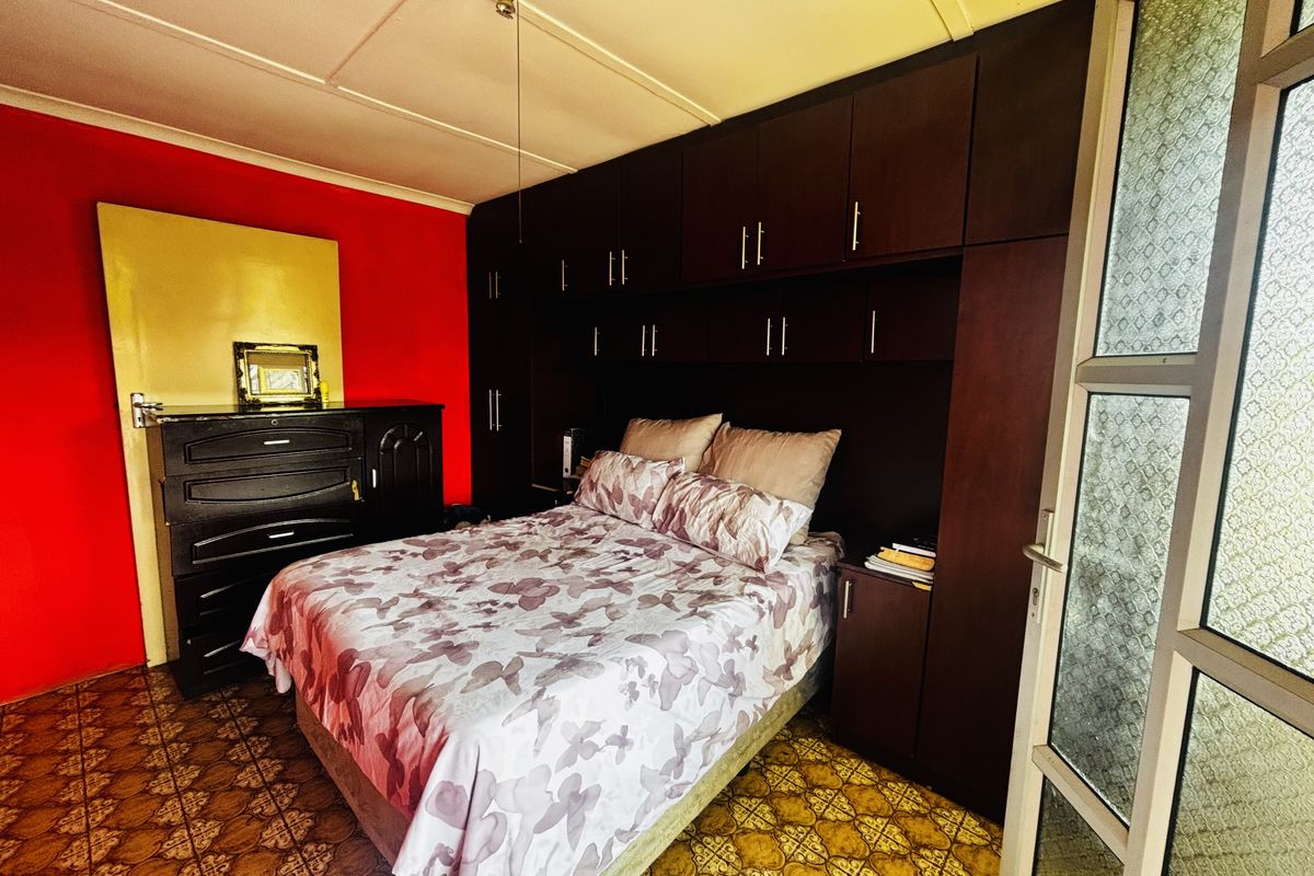 Bedroom featuring extensive dark wood built-in cabinetry, patterned floor tiles, and a bright red accent wall.