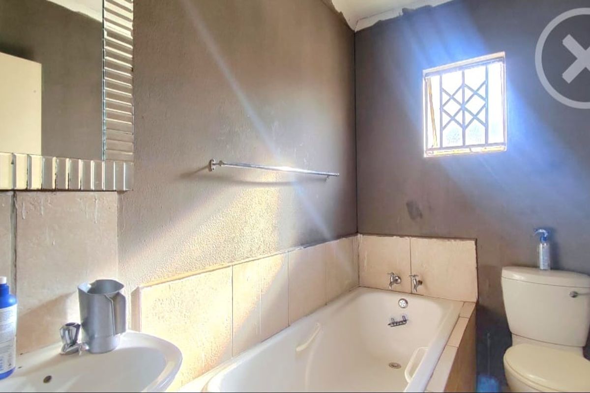 A functional bathroom featuring a bathtub, pedestal basin, and toilet, with unfinished wall surfaces requiring cosmetic attention and renovation.