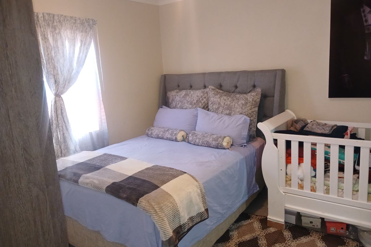 A functional bedroom featuring neutral wall finishes and a window with fitted curtaining.