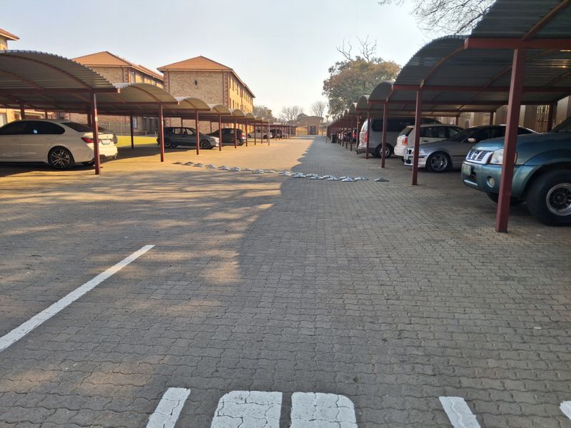 A paved outdoor parking area featuring multiple covered carport bays for residents.