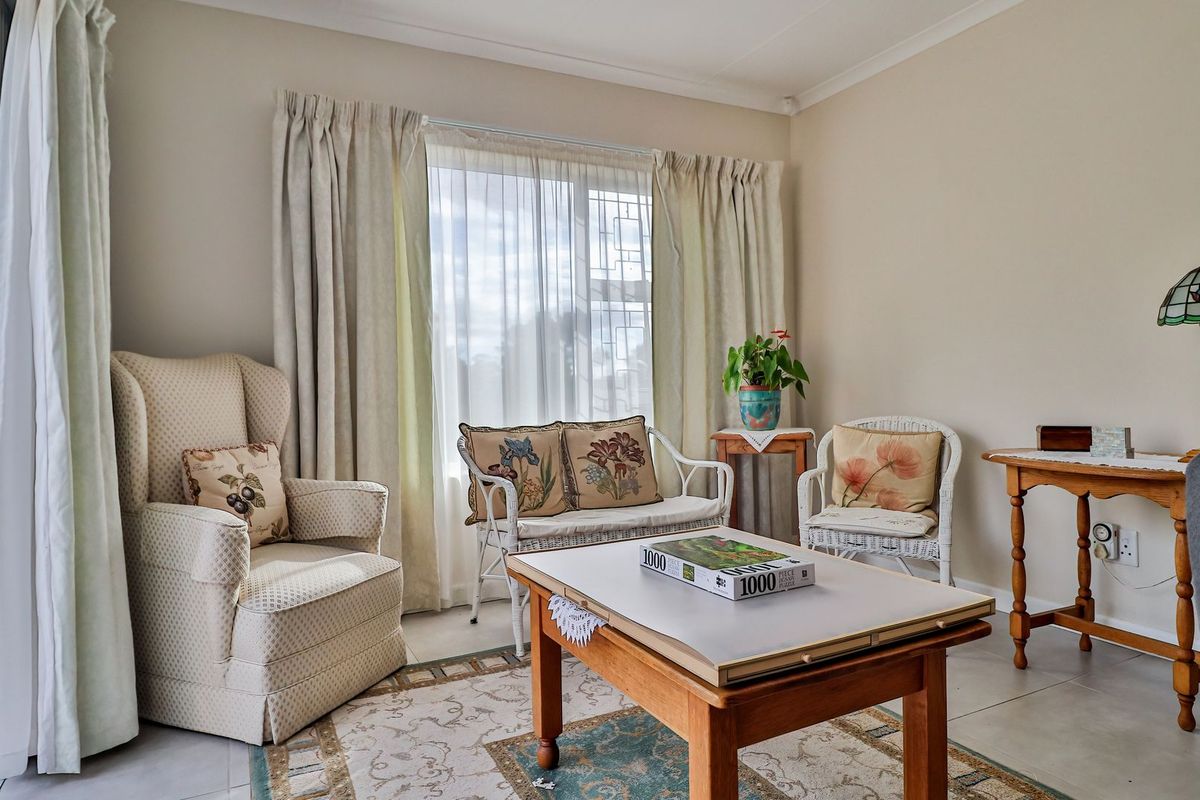 A bright living room featuring large windows with curtains, tiled flooring, and access to an outdoor area.