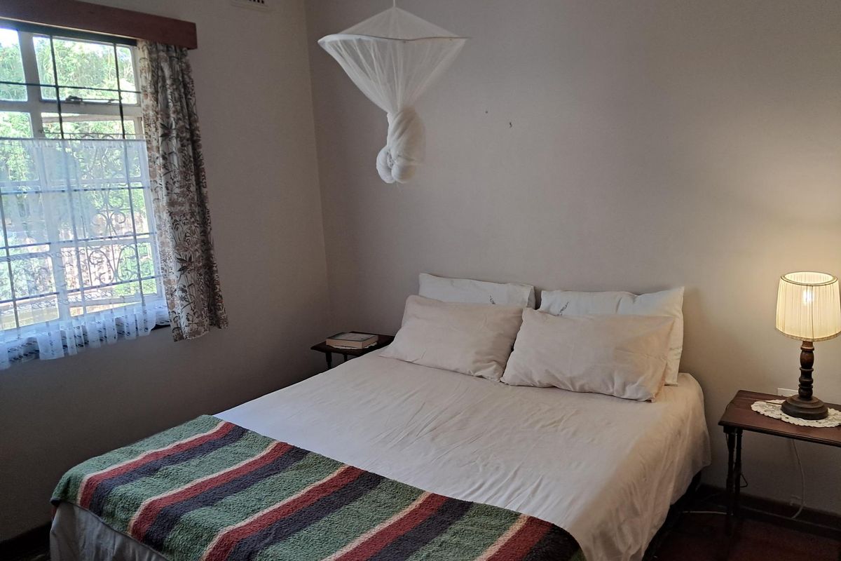 A functional bedroom featuring a window with security bars and a ventilation grille, providing a simple and comfortable living space.