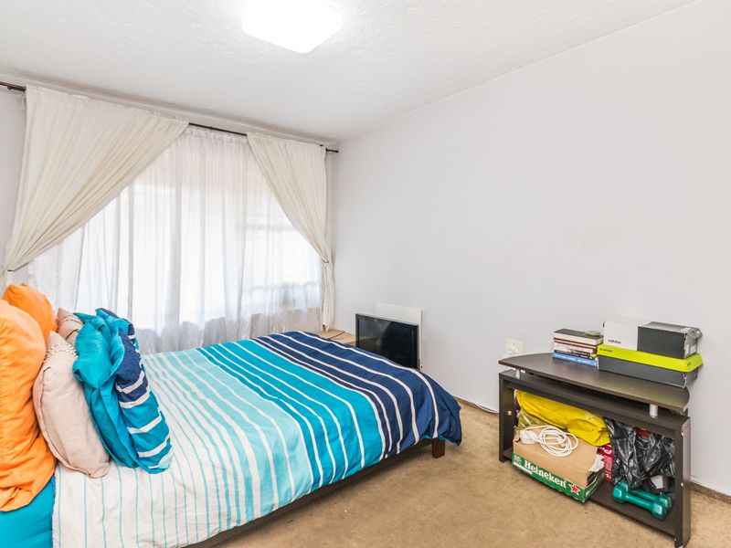 A standard bedroom featuring neutral walls, carpeted flooring, and a large window with installed curtain rods.