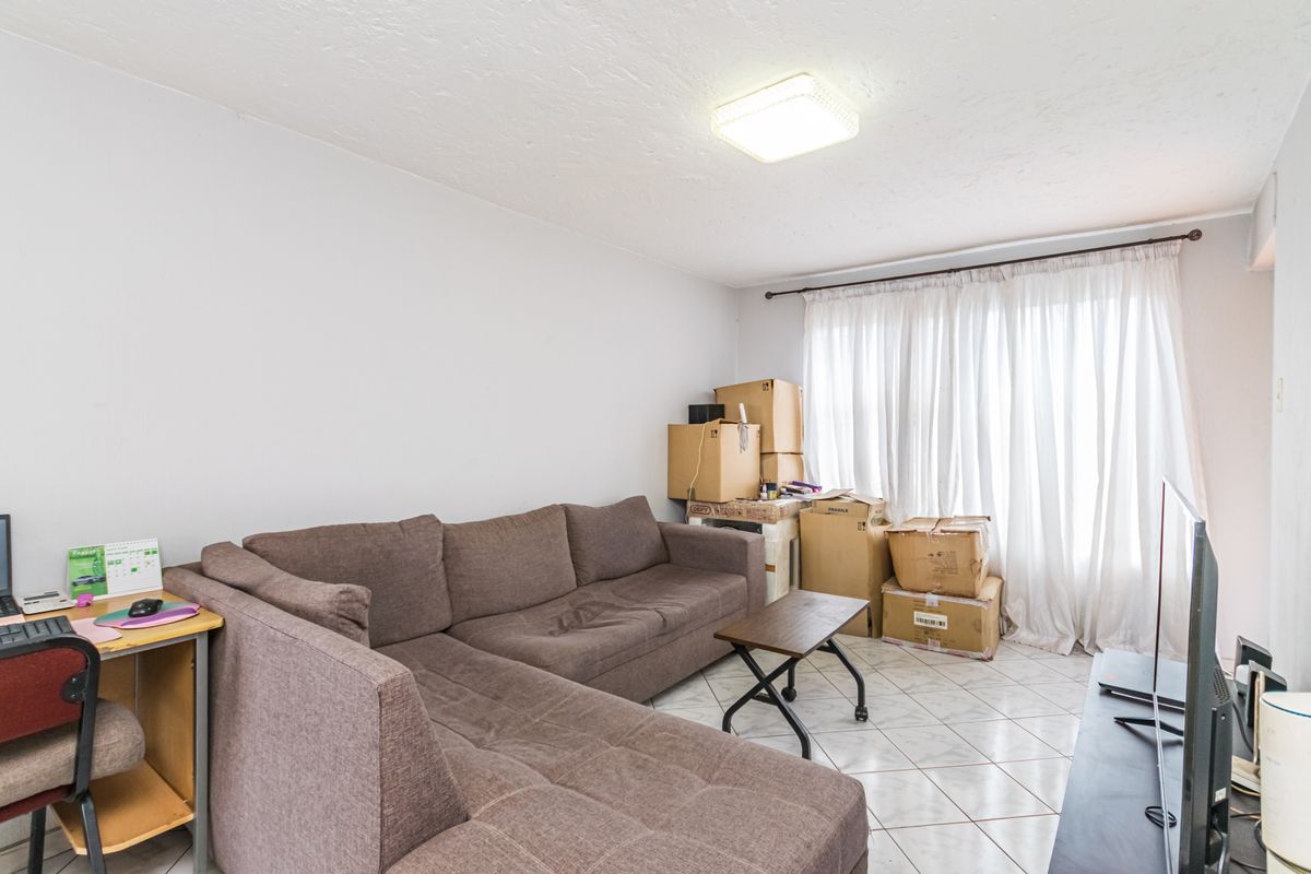 A living room area featuring tiled flooring and a central ceiling light fixture, offering a functional space ready for personalization.