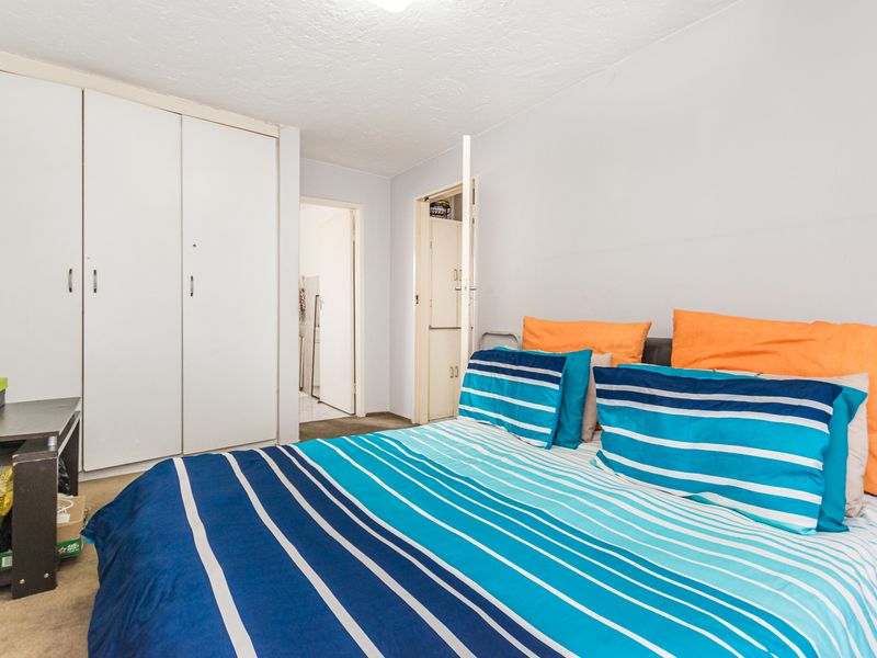 A functional bedroom featuring built-in cupboards and direct access to an adjoining room.