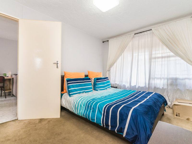 A standard bedroom featuring carpeted flooring and a window with curtain rods, providing a functional living space.